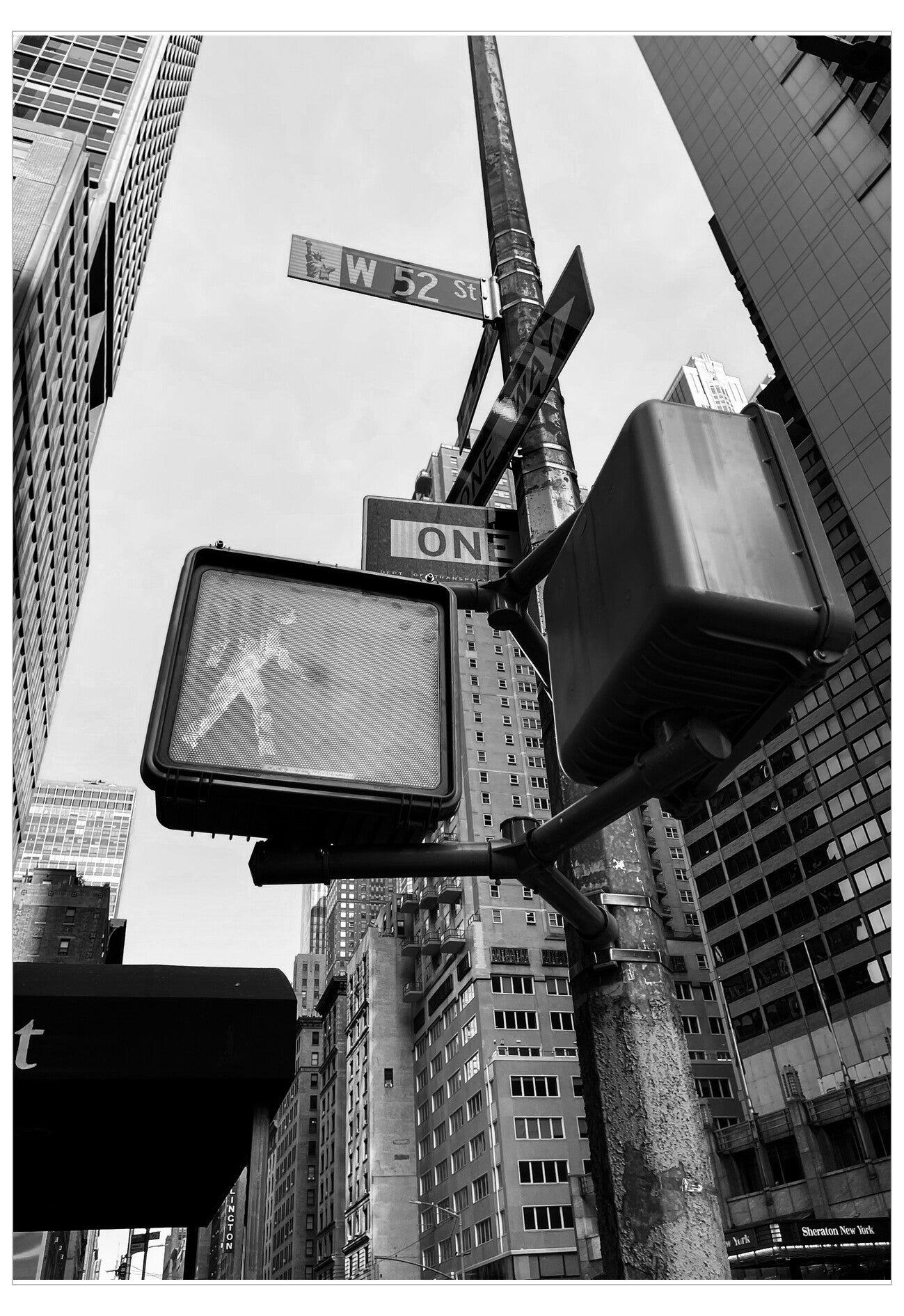 City street scene with traffic lights, street signs, and tall buildings.
