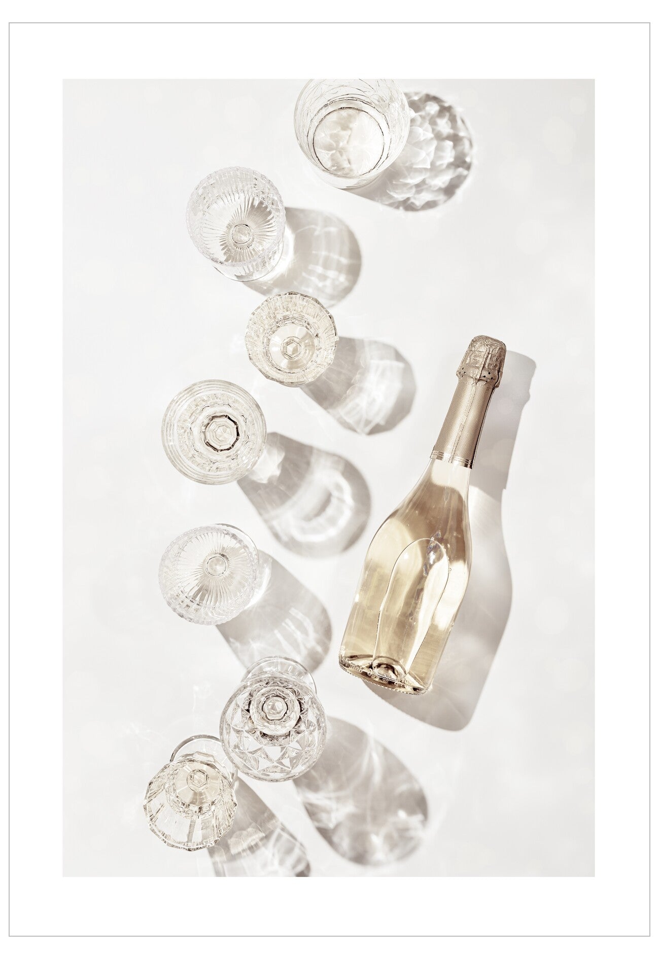 Gold champagne bottle surrounded by clear glass bottles on a white background