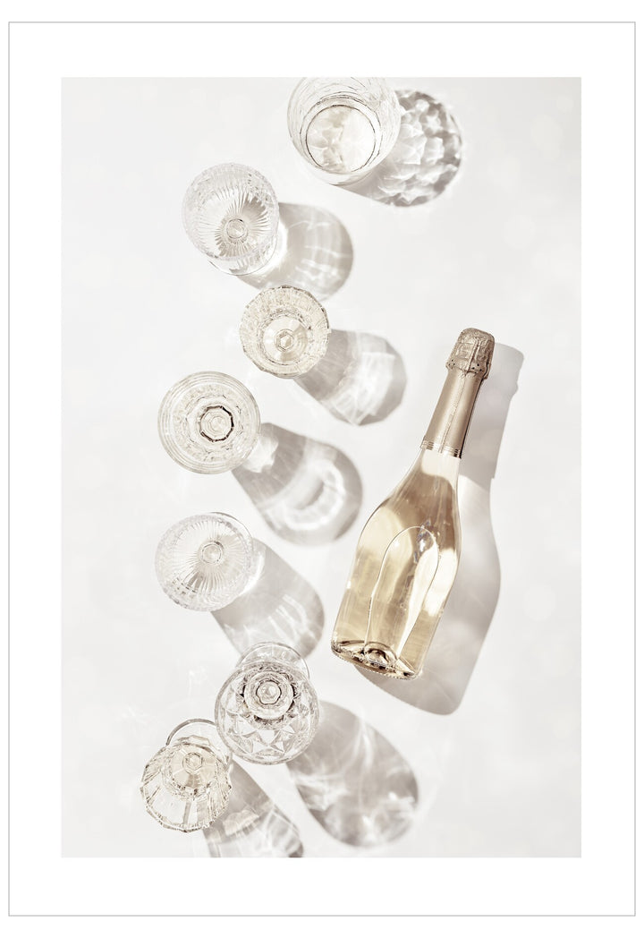 Gold champagne bottle surrounded by clear glass bottles on a white background