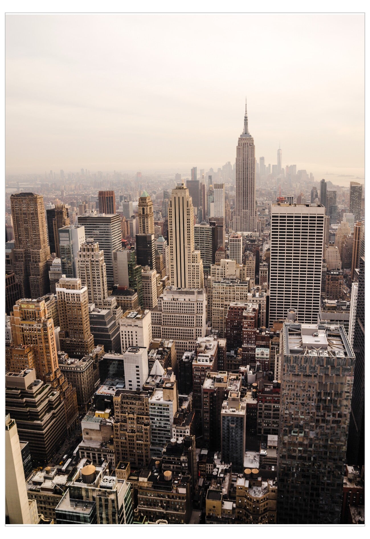 Cityscape with tall buildings, including the Empire State Building, under a hazy sky.