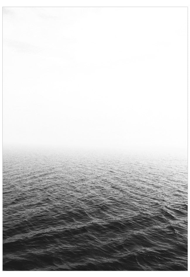 Black and white photograph of a calm ocean with a light gradient.