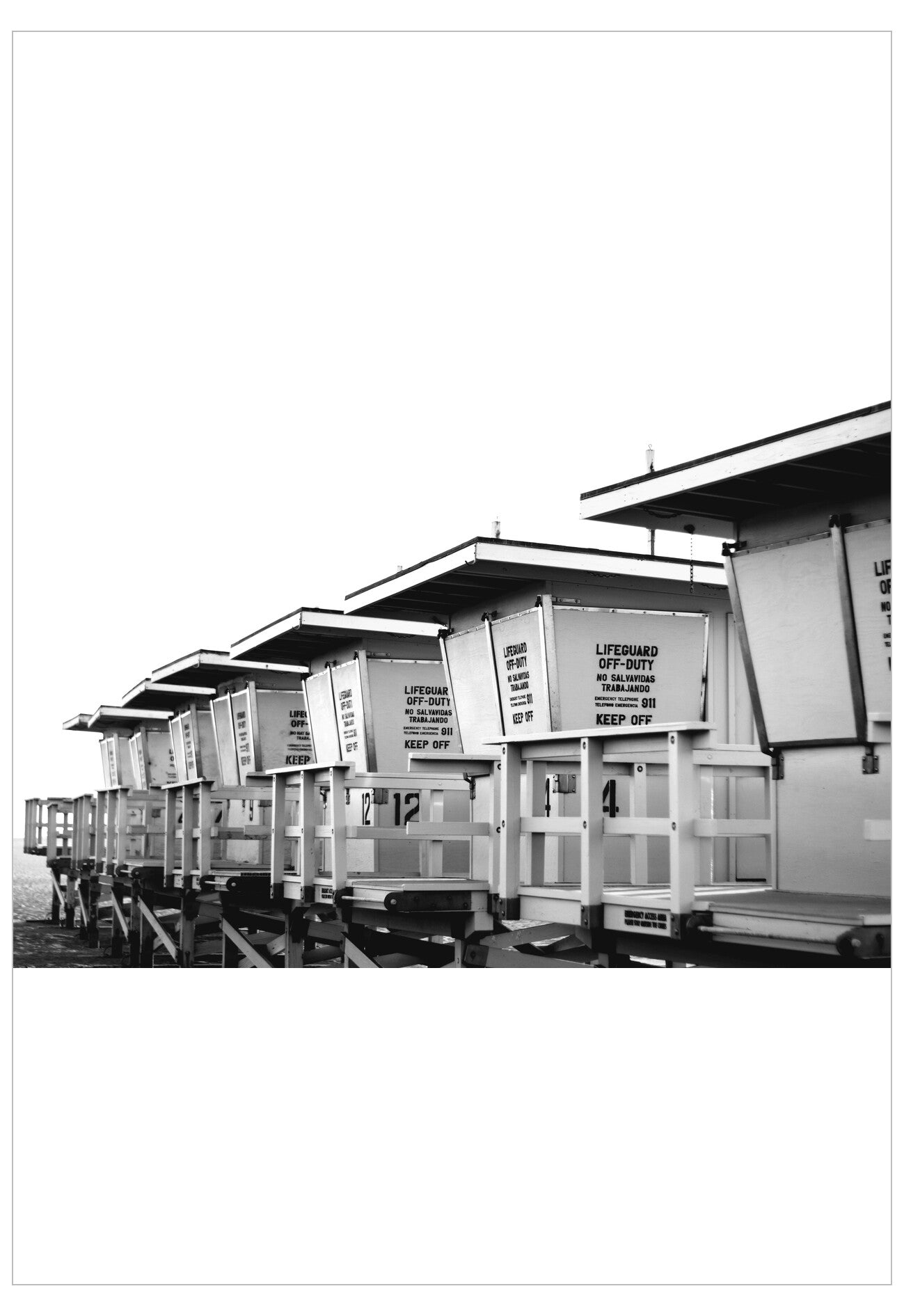 Black and white photo of a row of beach huts with signs on a white background