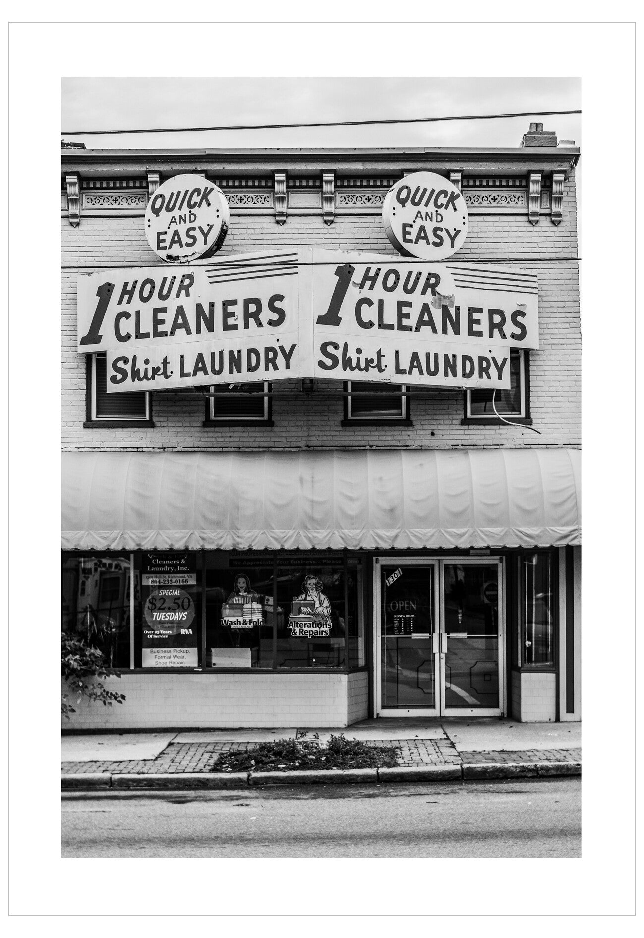 Vintage black and white photo of a cleaners and laundry store with large sign.