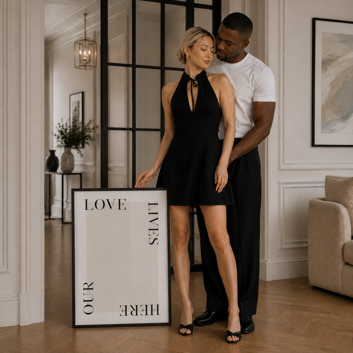 Man and woman standing in a stylish room with a 'Love Lives Here' sign.