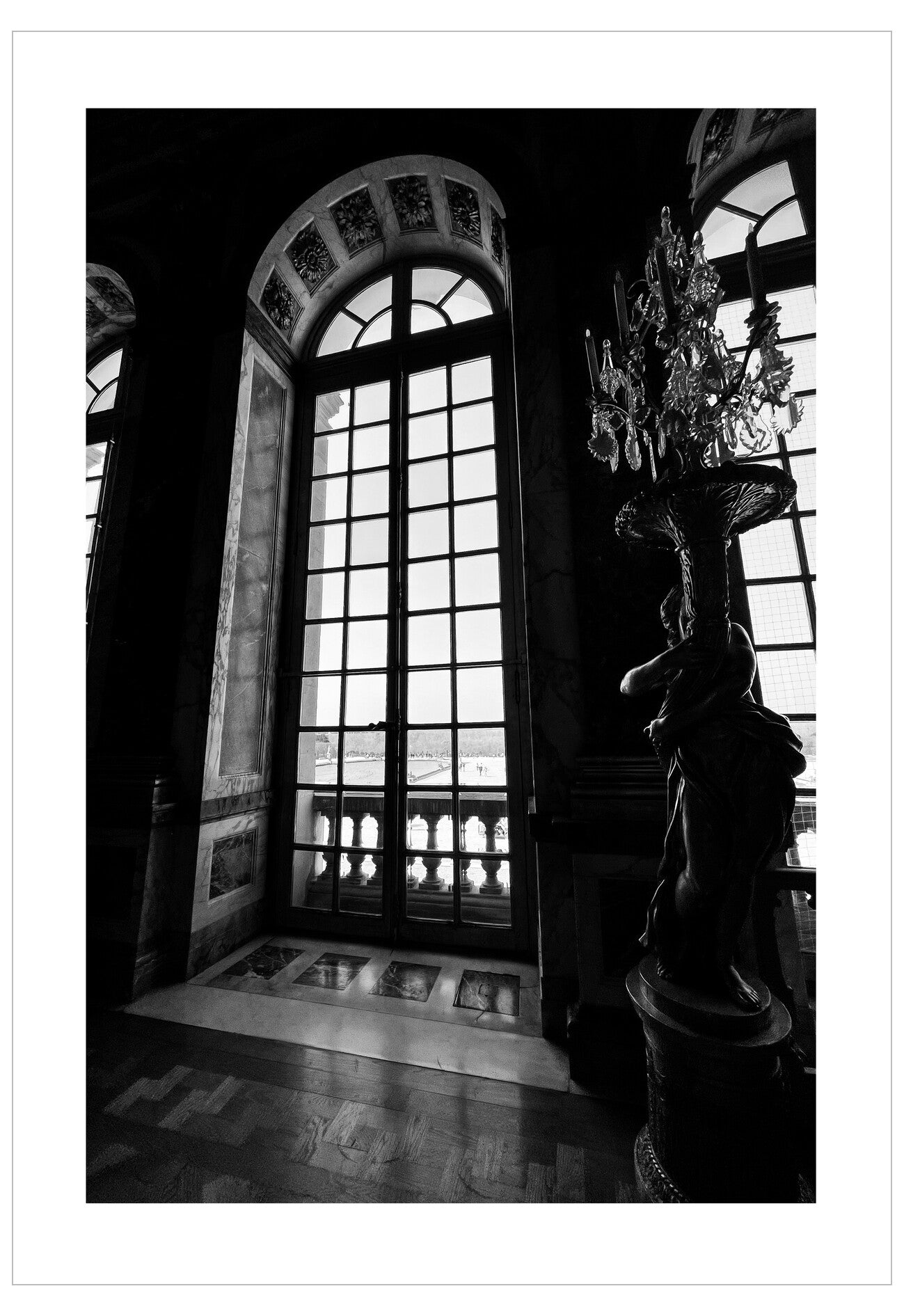 Black and white interior scene with a large window and decorative chandelier.
