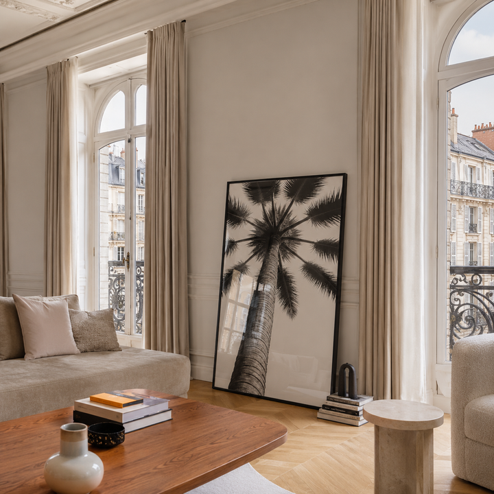 Living room with a large window, sofa, coffee table, and decorative palm tree painting.