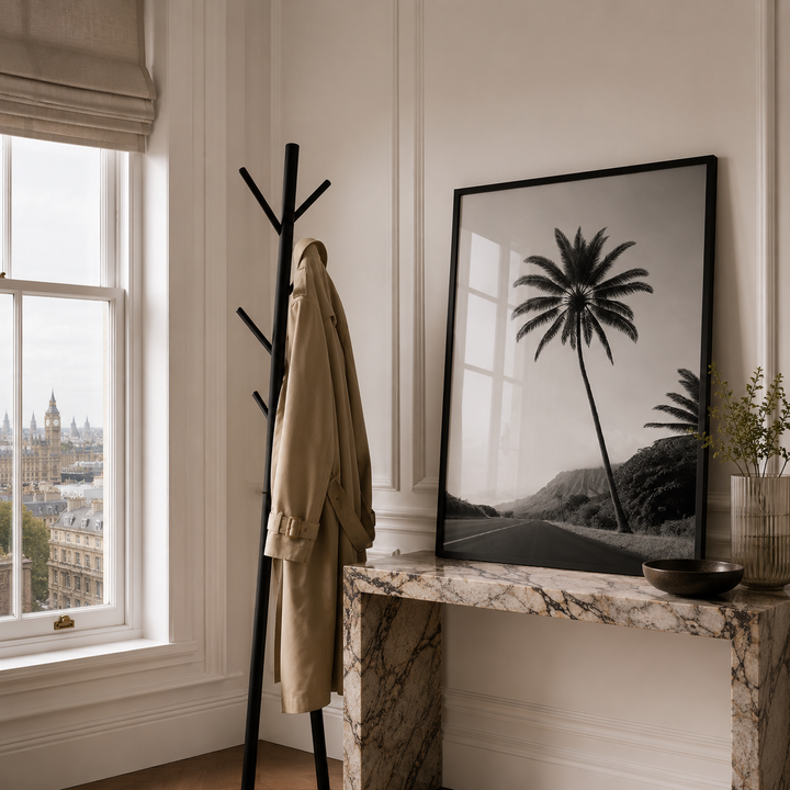 Room interior with coat rack, framed palm tree print, and window view.