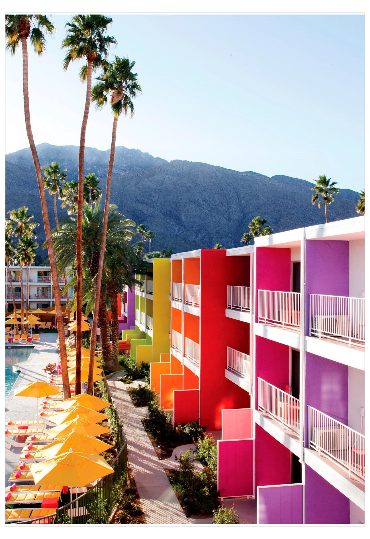 Colorful hotel building with palm trees and mountains in the background