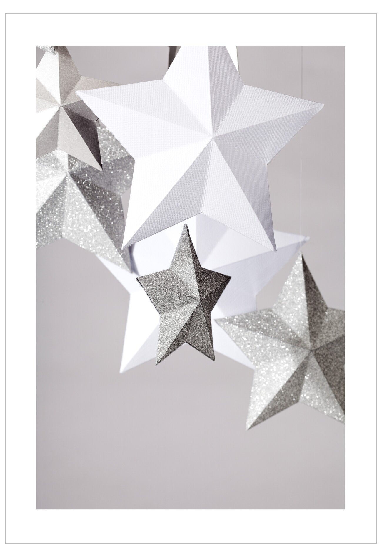Decorative paper stars in white, gray, and silver on a light gray background