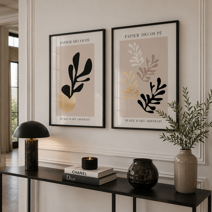 Two framed botanical prints on a wall above a console table with decorative items.