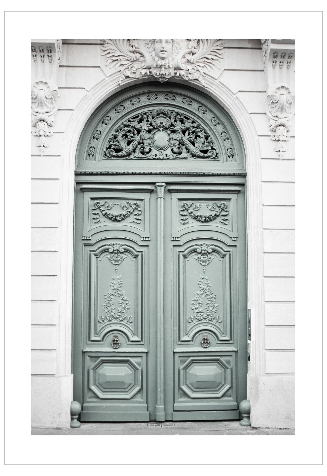 Decorative green door with intricate carvings on a white wall