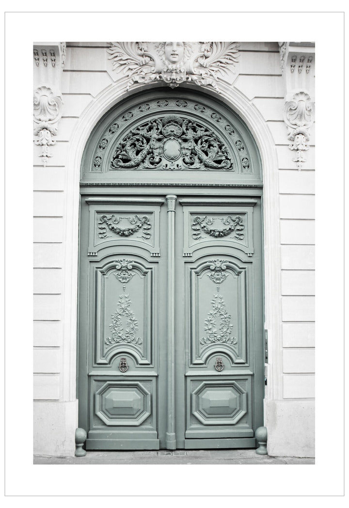 Decorative green door with intricate carvings on a white wall