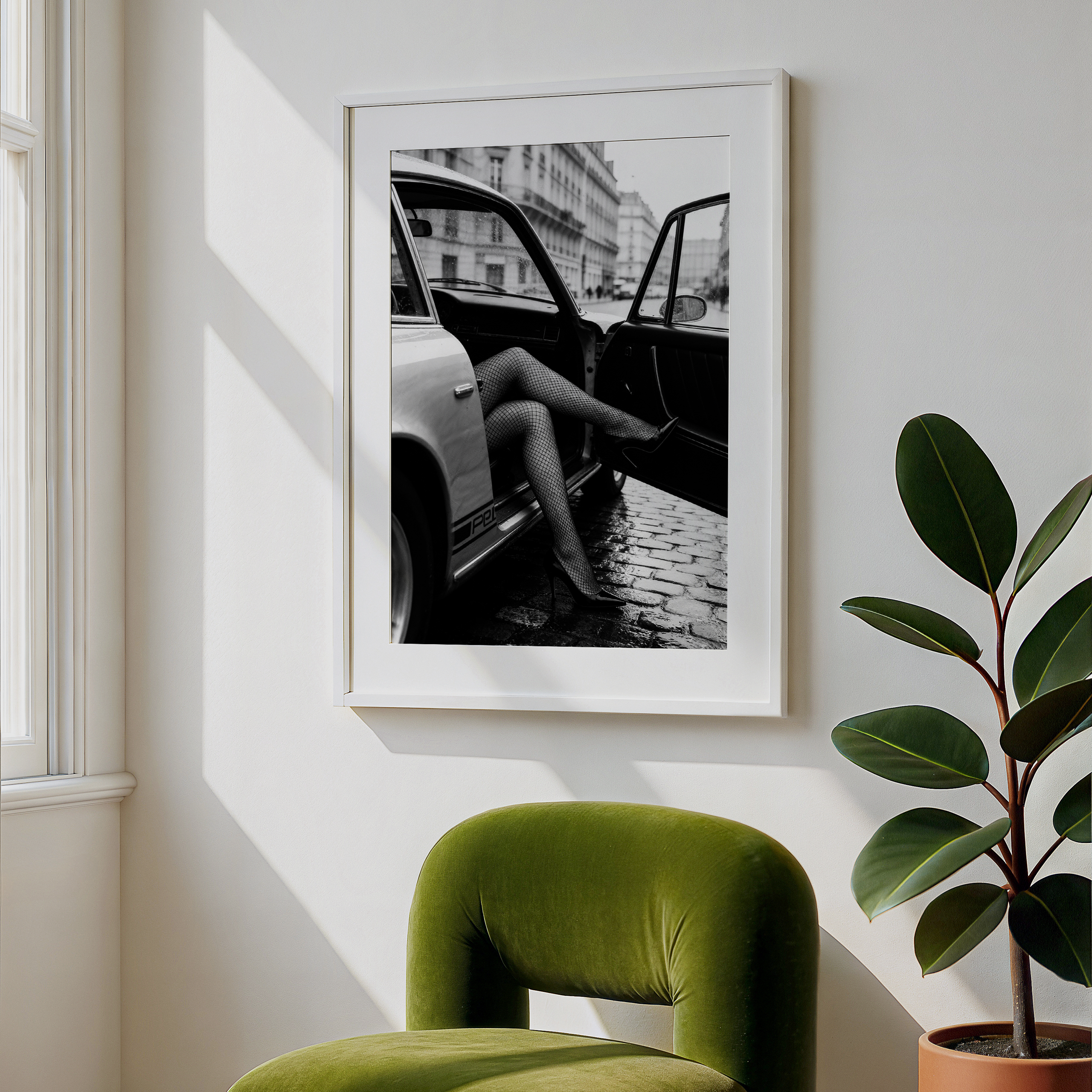 Green chair in a room with a framed black and white photo on the wall and a potted plant.