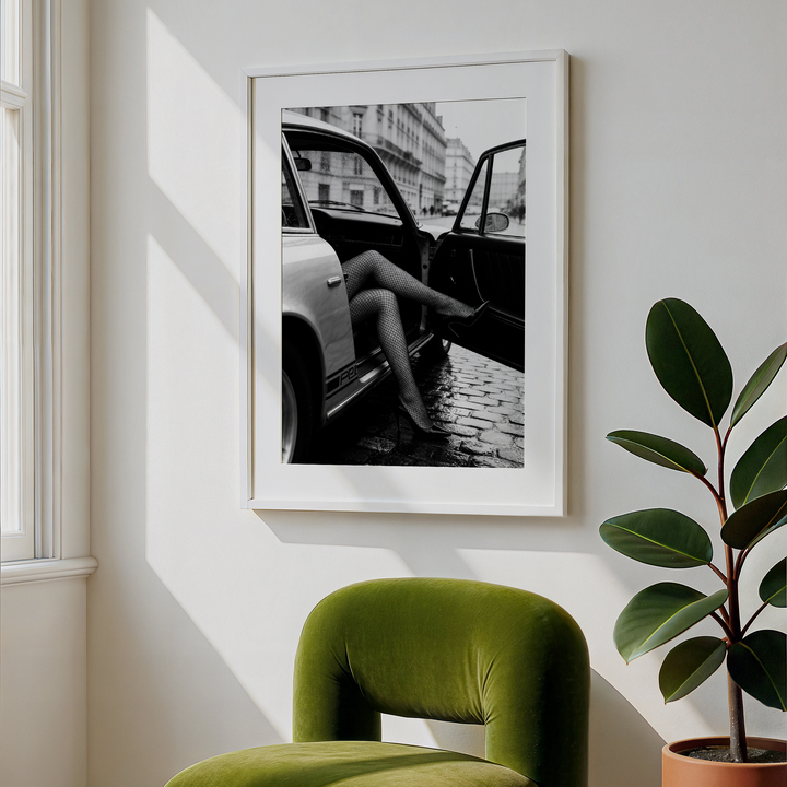 Green chair in a room with a framed black and white photo on the wall and a potted plant.