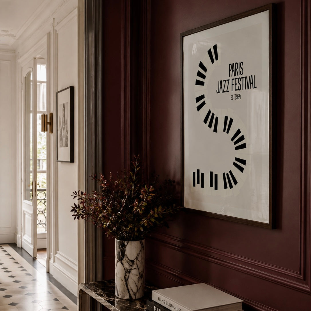 A framed minimalist art print featuring a black circular 'S' design with the text 'PARIS JAZZ FESTIVAL EIFFEL' on a white background, hanging on a dark burgundy paneled wall in an elegant hallway.