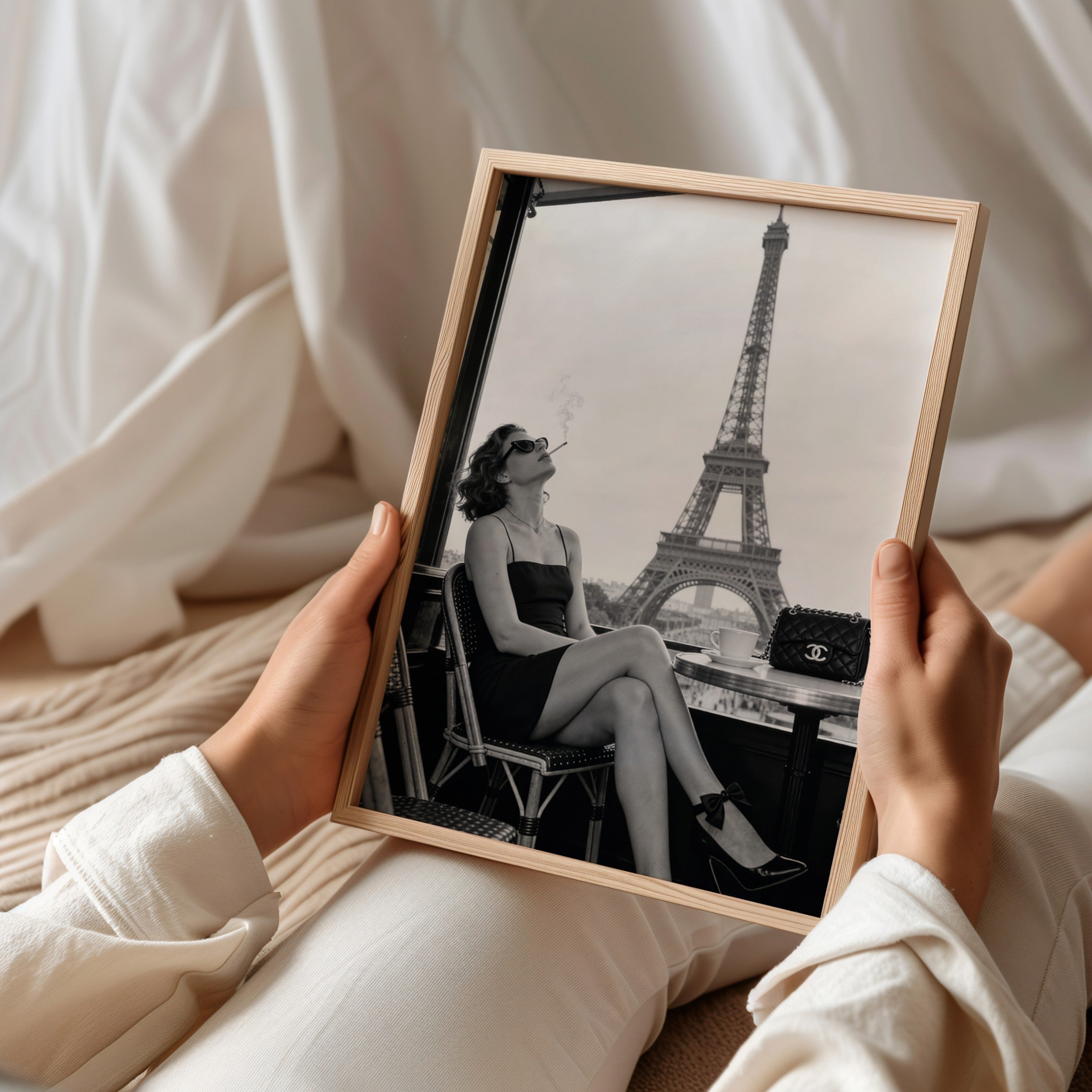 Person holding a framed black and white photo of a woman smoking by the Eiffel Tower.