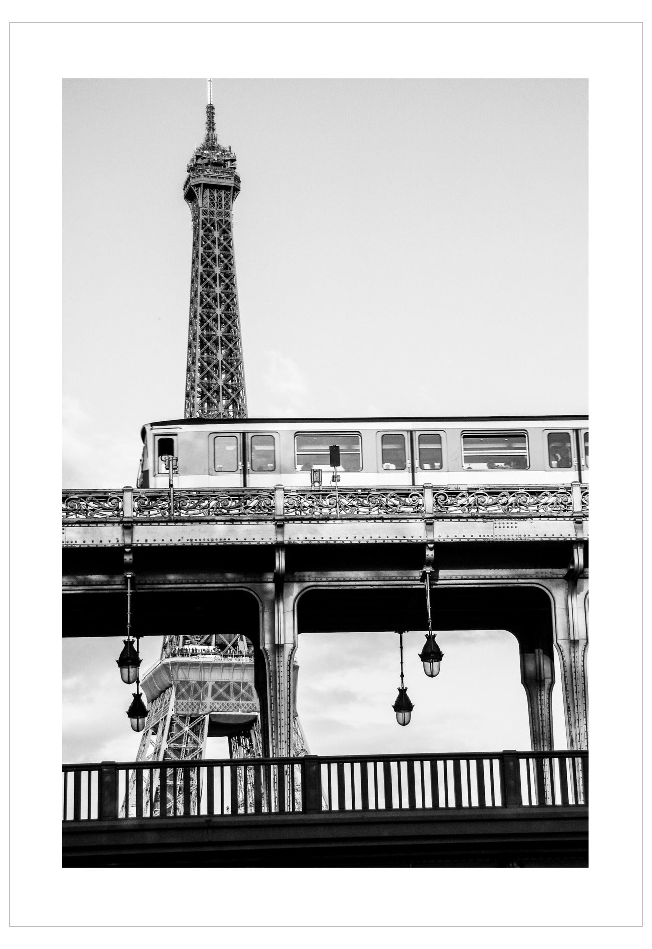 Black and white photo of a train crossing under the Eiffel Tower