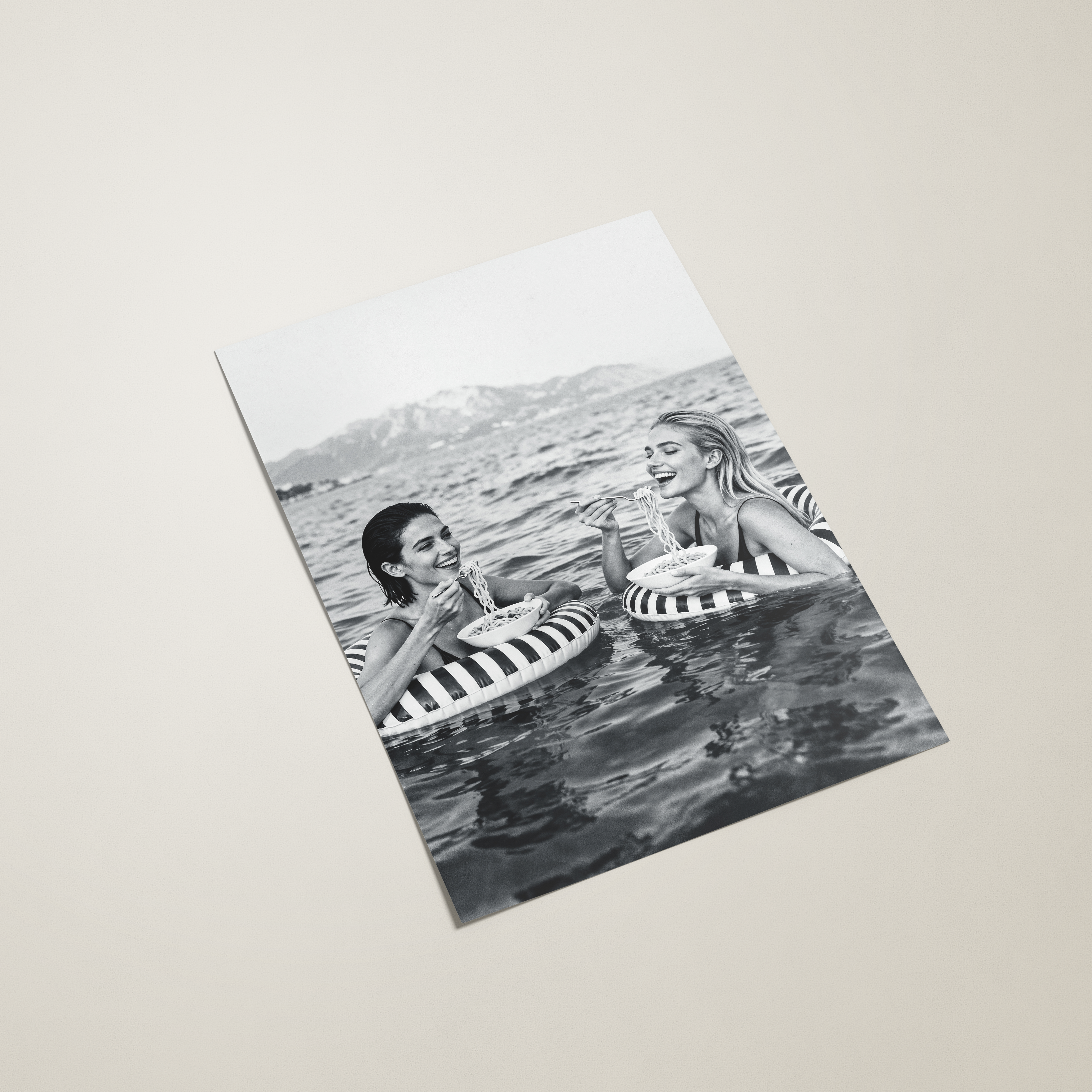 Black and white photo of two people with striped floats on a light beige background