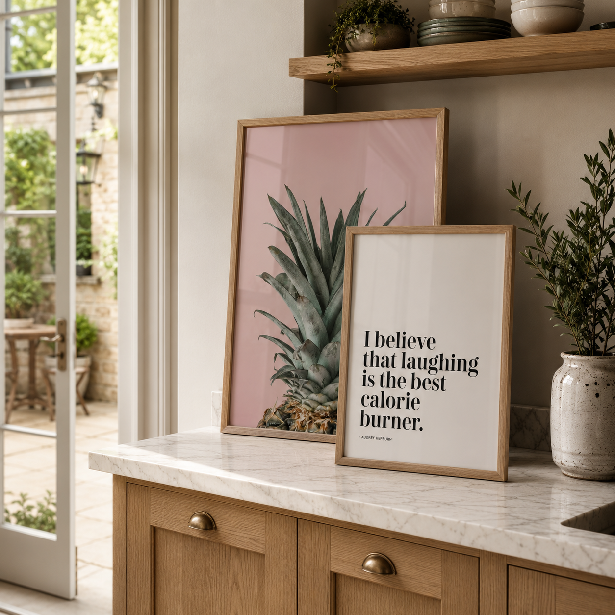 Framed prints on a kitchen counter with a pineapple illustration and motivational quote.