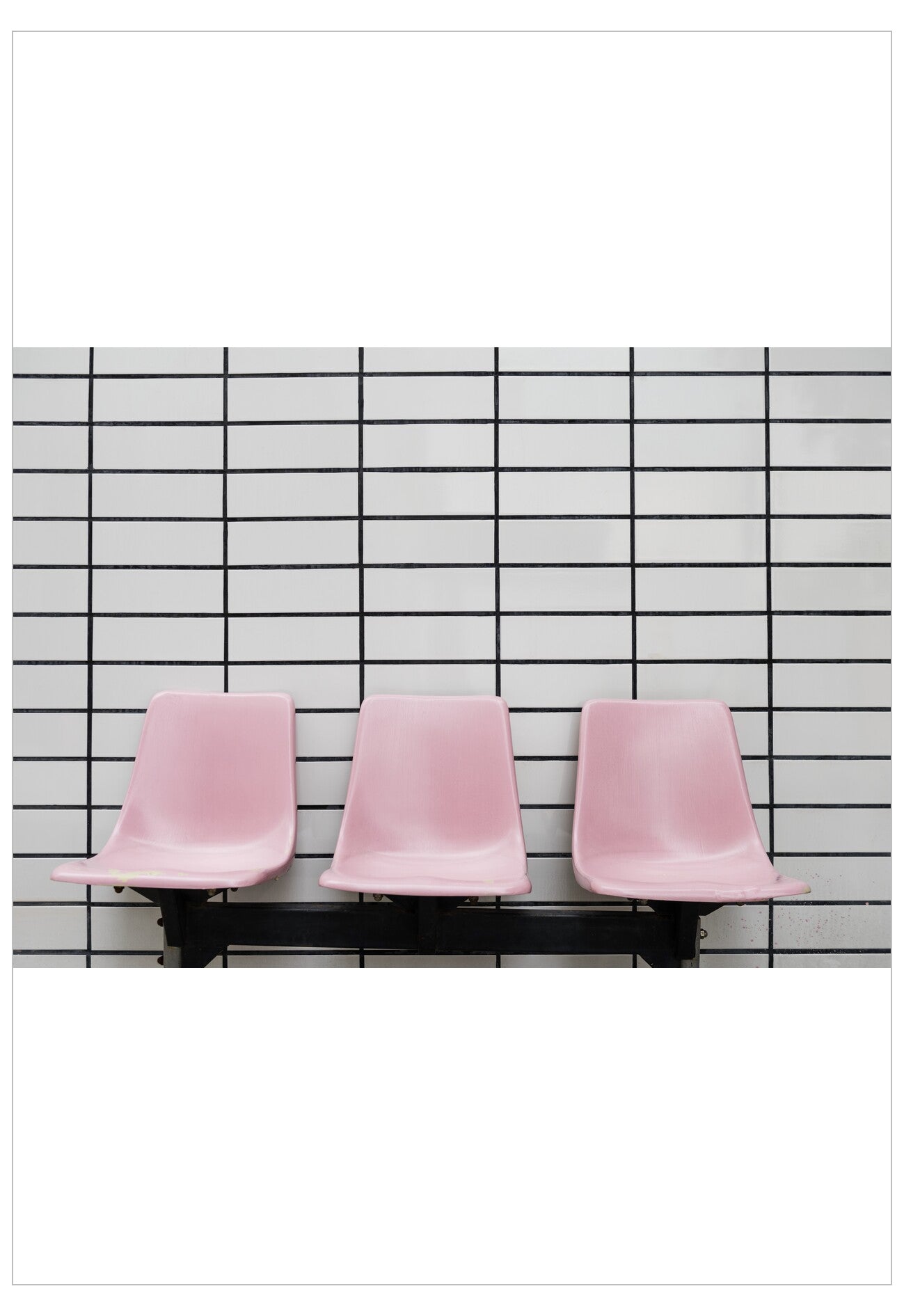 Three pink chairs lined up against a black and white grid wall.