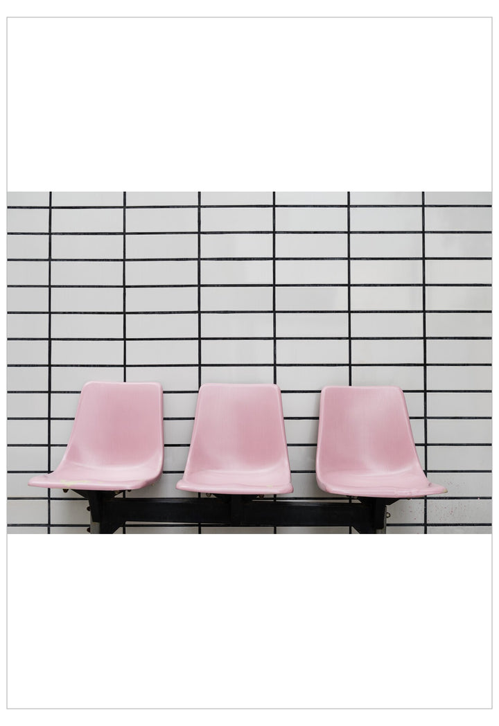 Three pink chairs lined up against a black and white grid wall.