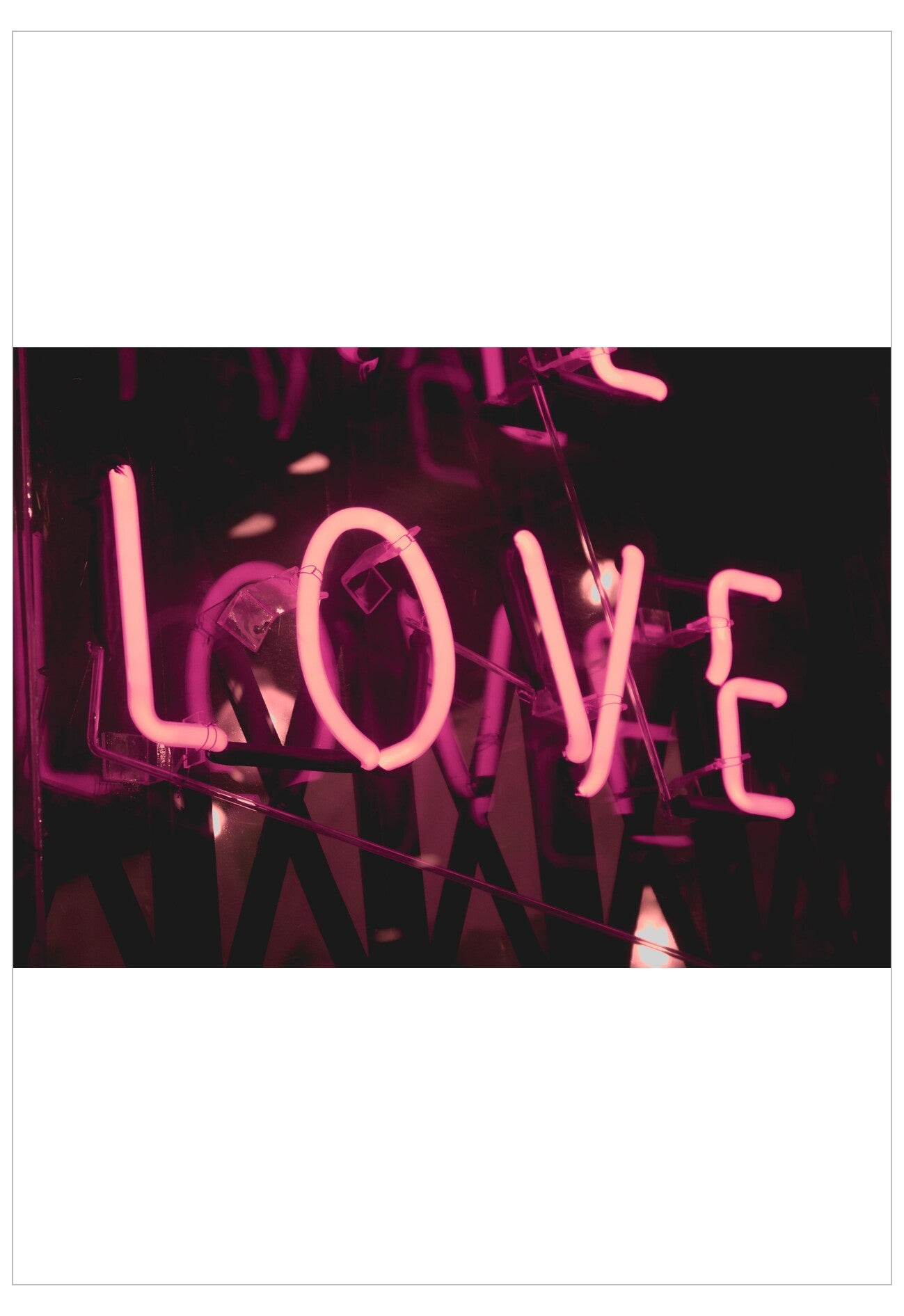 Neon sign spelling 'LOVE' in pink on a black background
