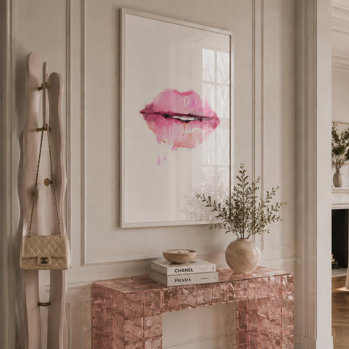 Decorative console table with a pink lip art piece on the wall in a stylish room.