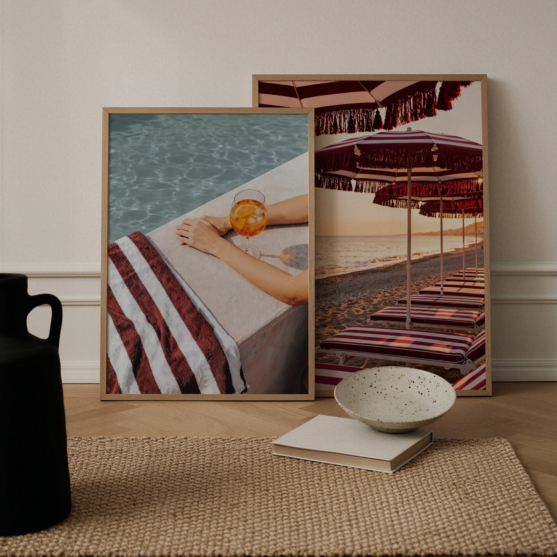 Two framed artworks on a wooden floor with a bowl and books.