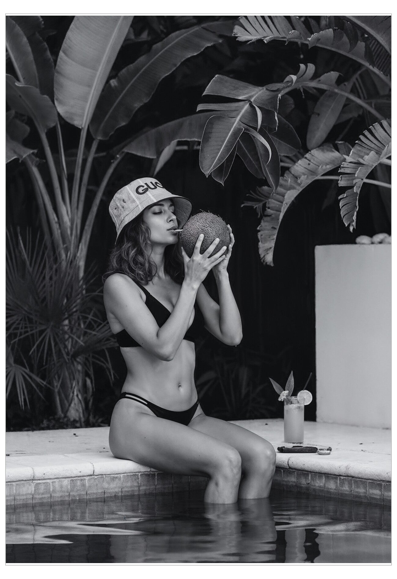 Woman in a swimsuit sitting by a pool with plants in the background
