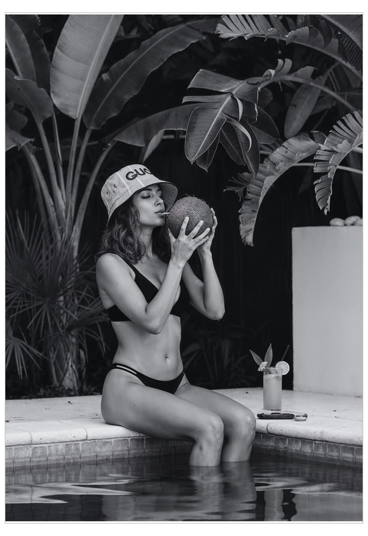 Woman in a swimsuit sitting by a pool with plants in the background