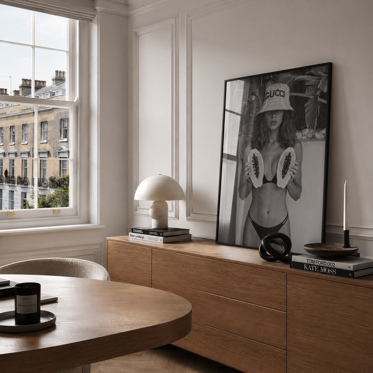 Modern interior with wooden dresser, framed Gucci poster, and books.