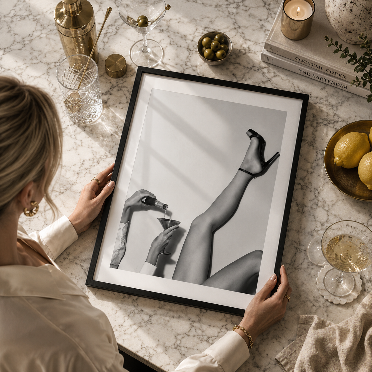 woman holding black and white framed art of a woman pouring champagne with one leg in the air