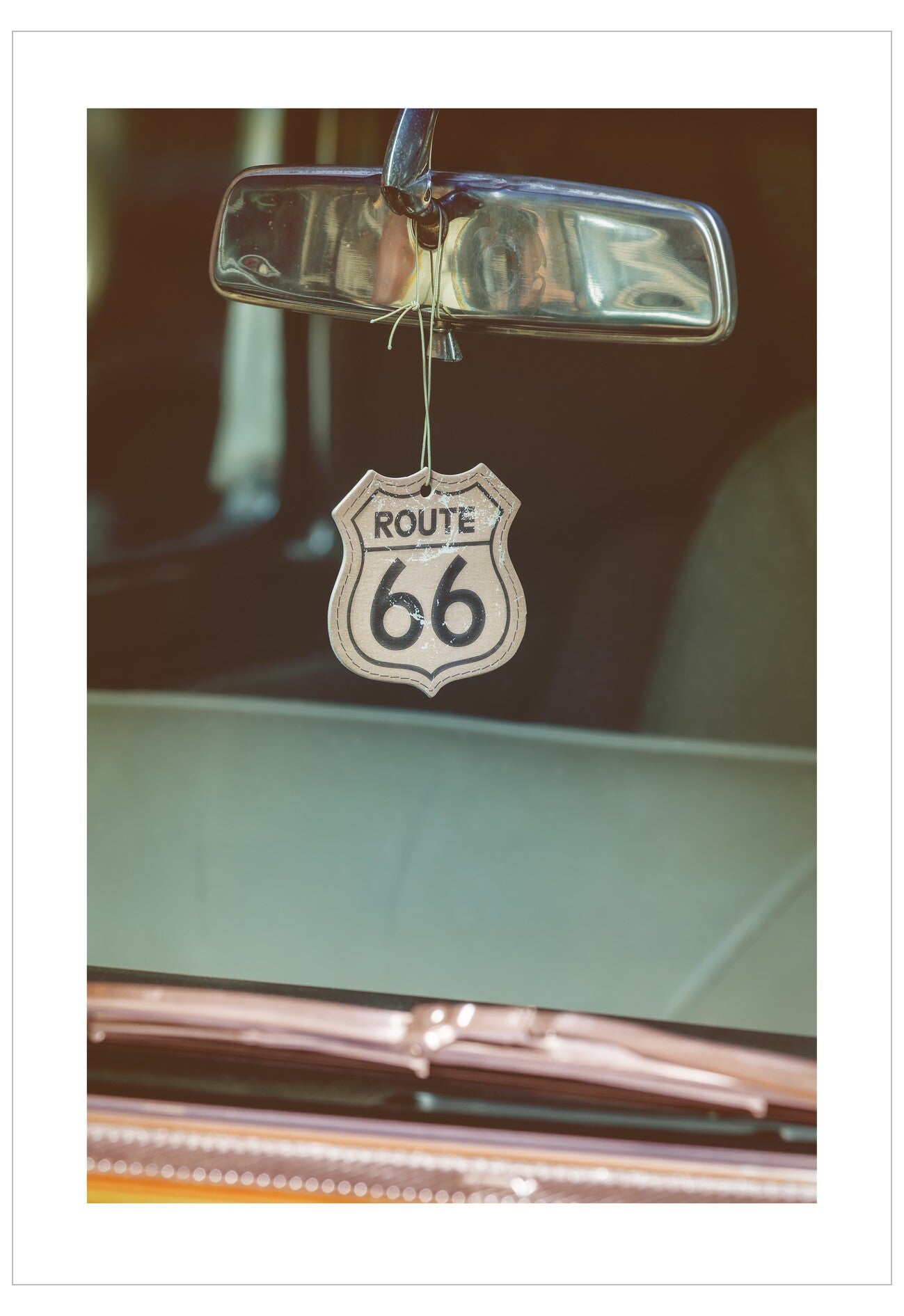 Car rearview mirror with a Route 66 sign hanging from it.