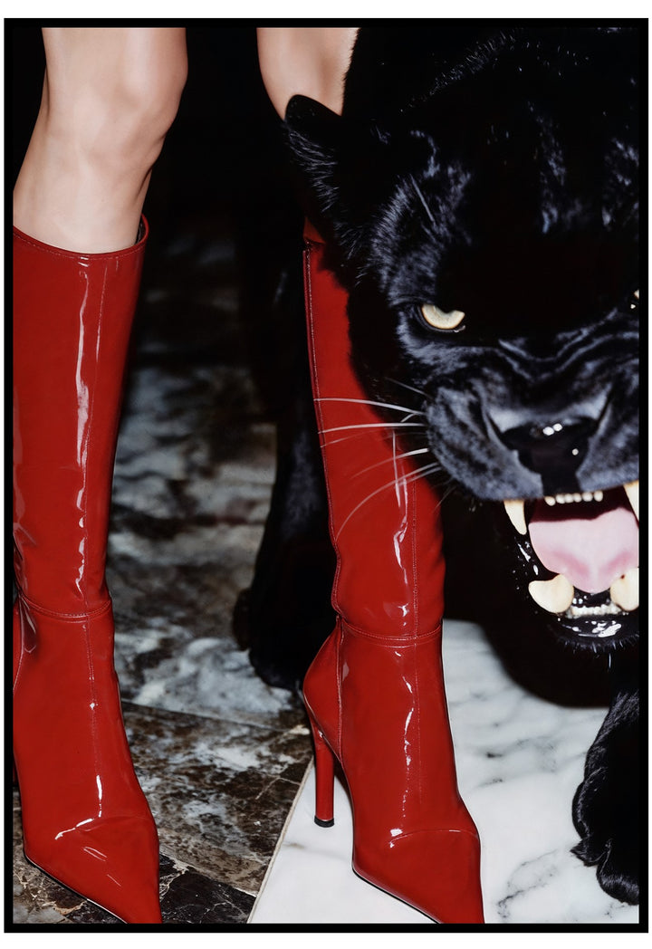 Red high-heeled boots with a black panther cutout on a marble surface