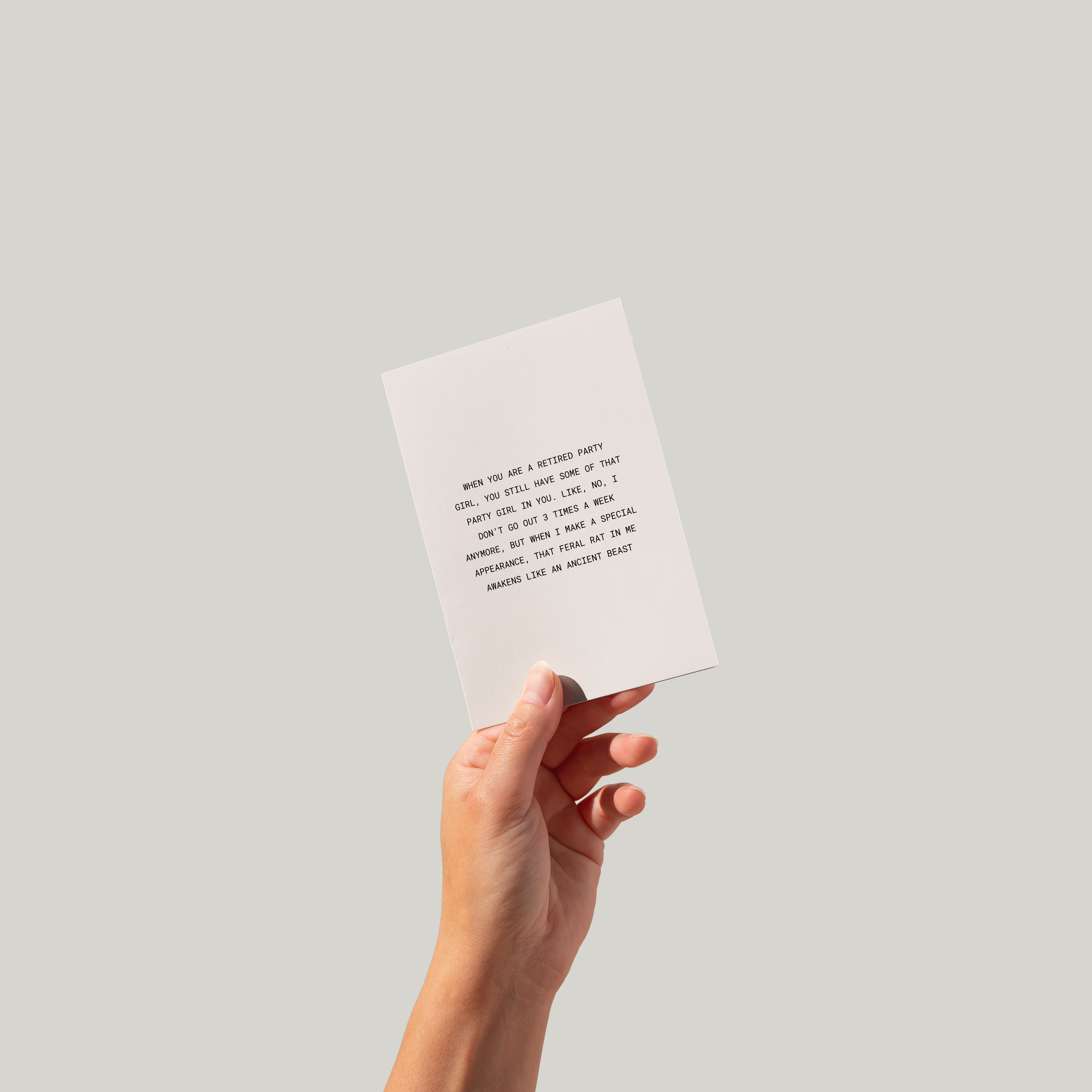 Hand holding a greeting card with text against a plain background