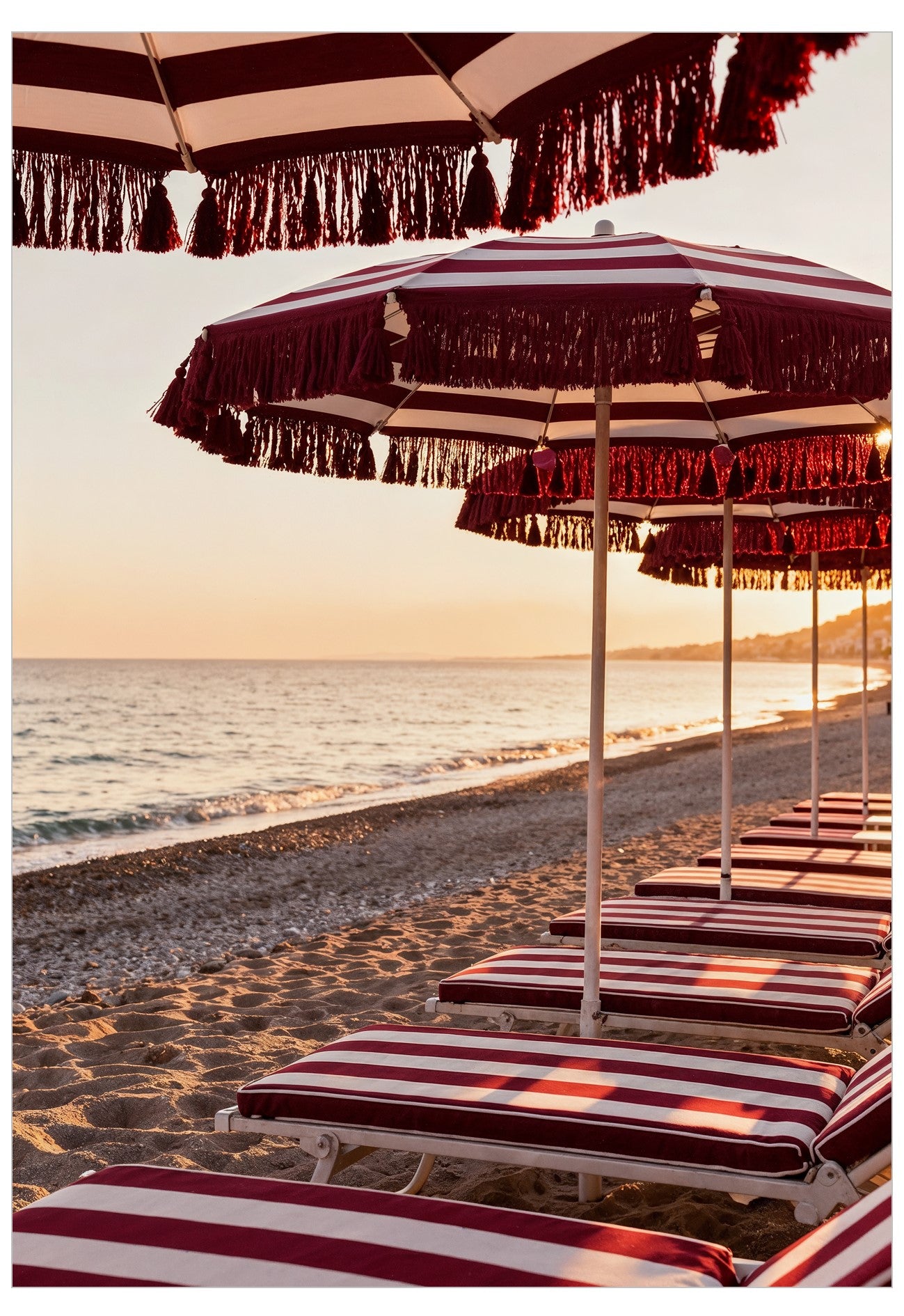 Beach scene with red and white striped umbrellas and lounge chairs on a sandy shore.