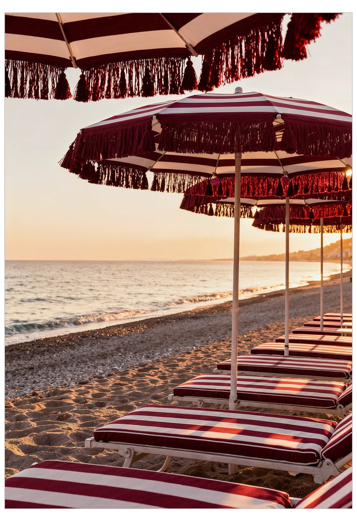 Beach scene with red and white striped umbrellas and lounge chairs on a sandy shore.