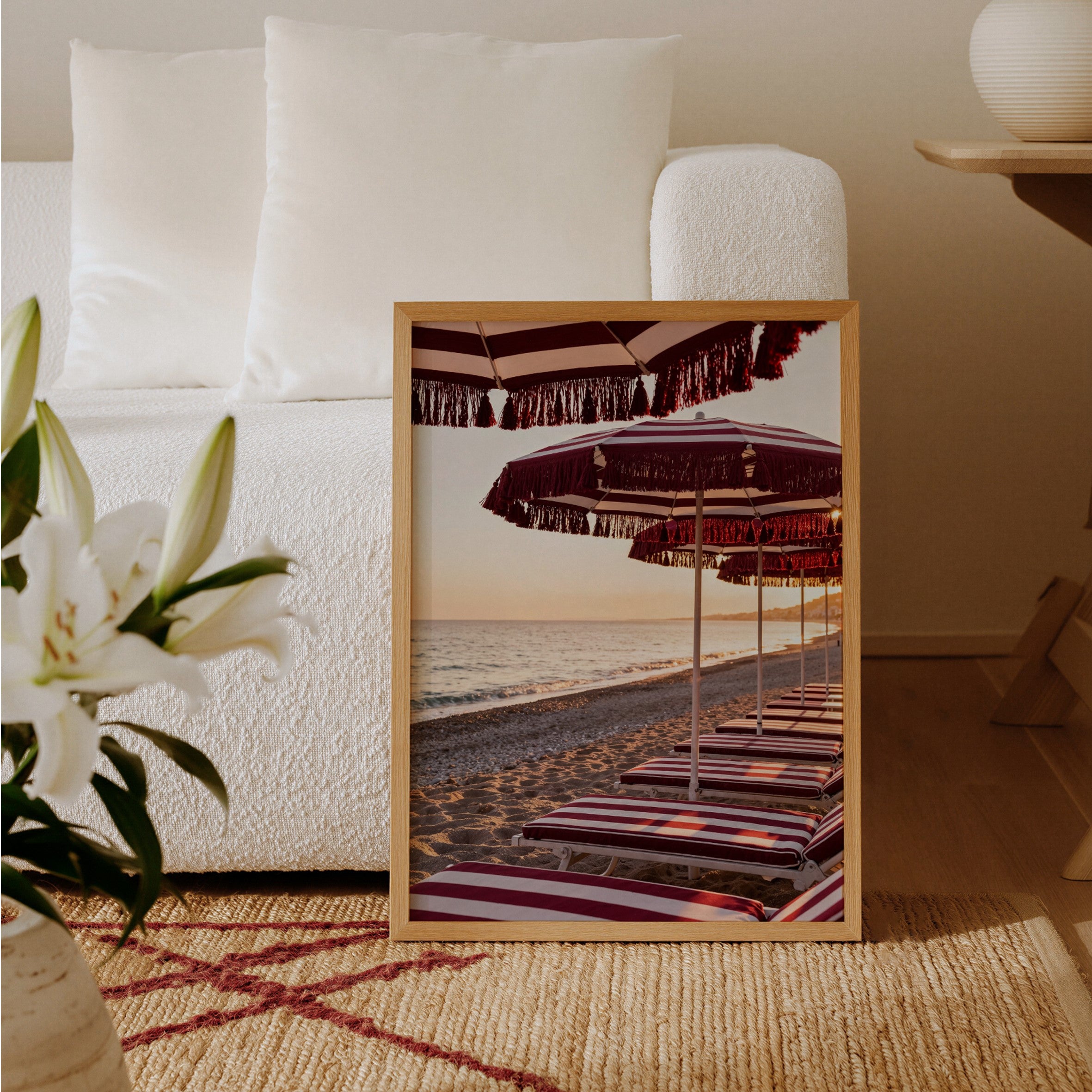 Framed beach scene with striped umbrellas on a side table in a living room.