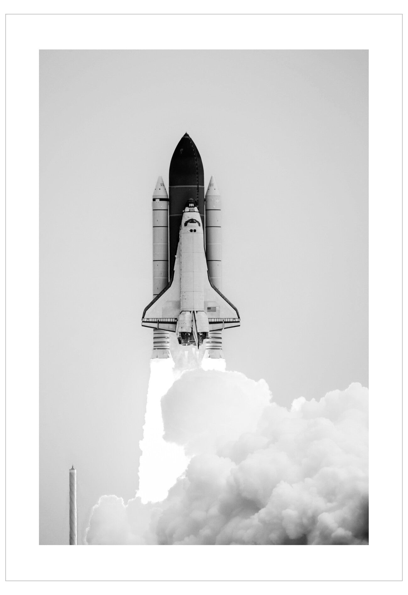 Black and white image of a space shuttle launch with smoke trail.