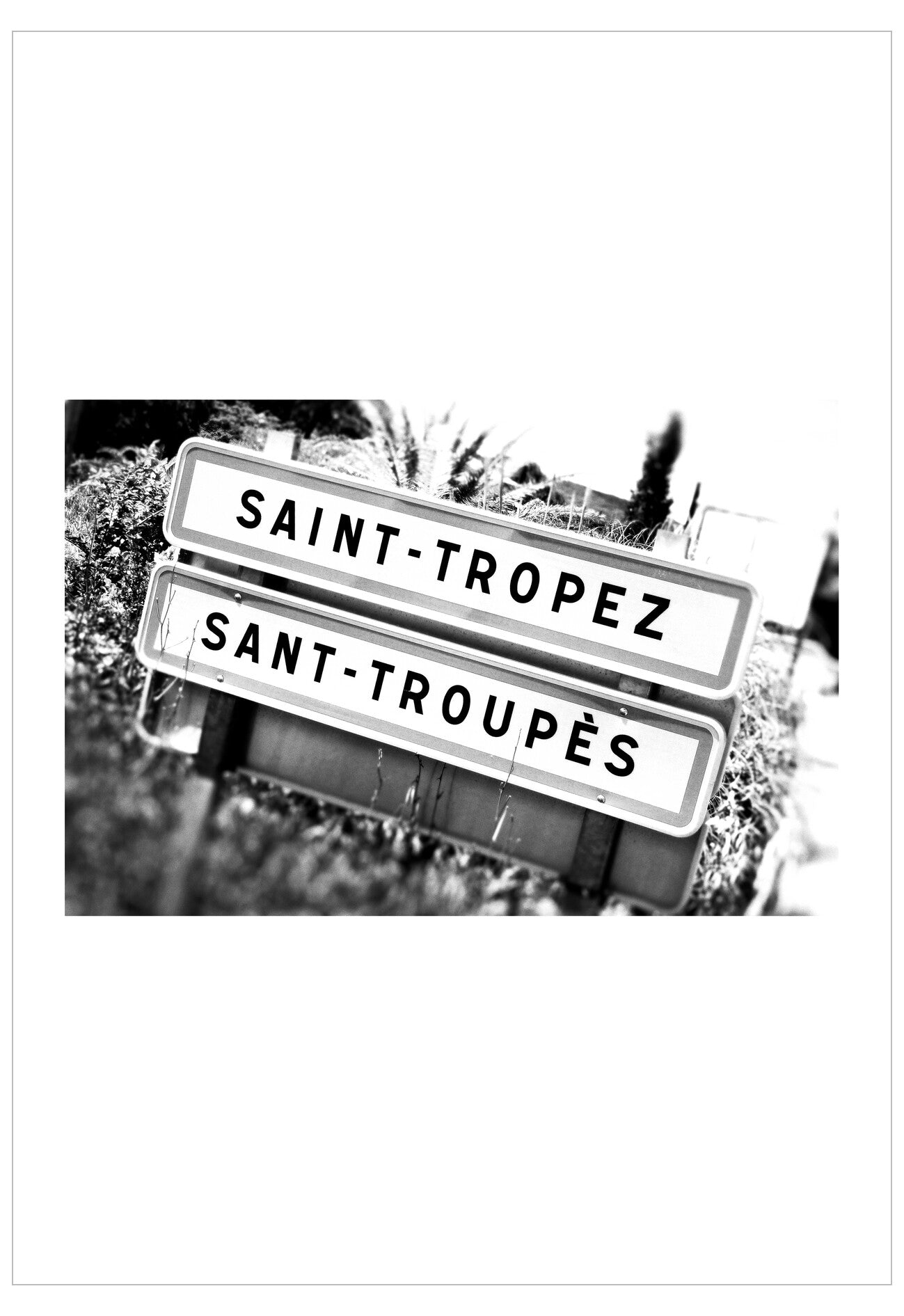 Black and white image of a road sign with 'Saint-Tropez' and 'Sant-Troupès' text.