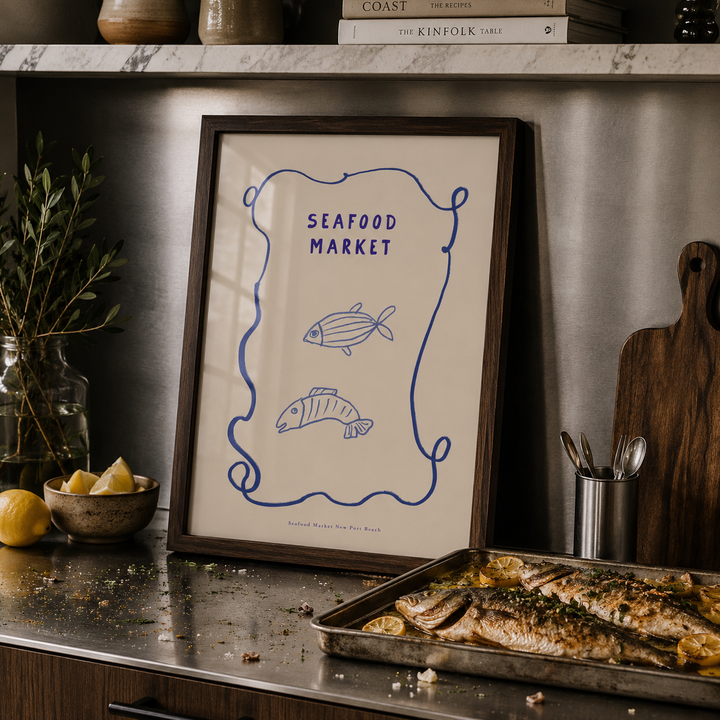 Framed artwork titled 'Seafood Market' on a kitchen counter with cooked fish.