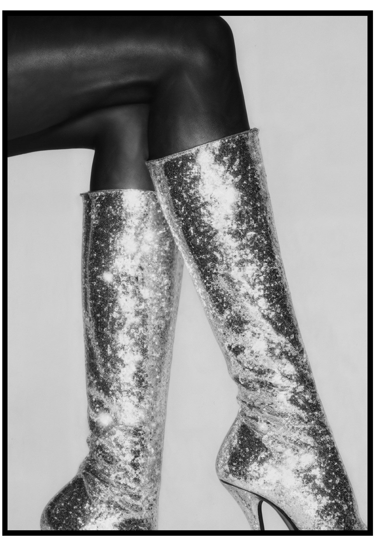 Silver sequin knee-high boots worn with black tights on a light background