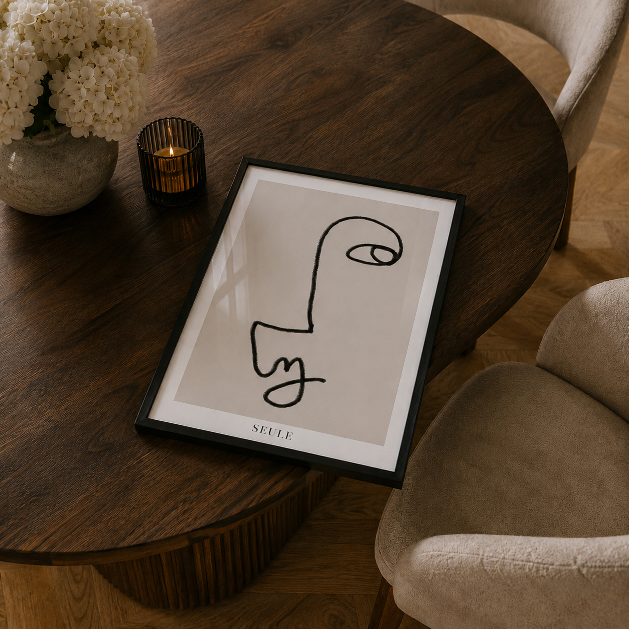Framed abstract art on a wooden table with a candle and decorative elements.