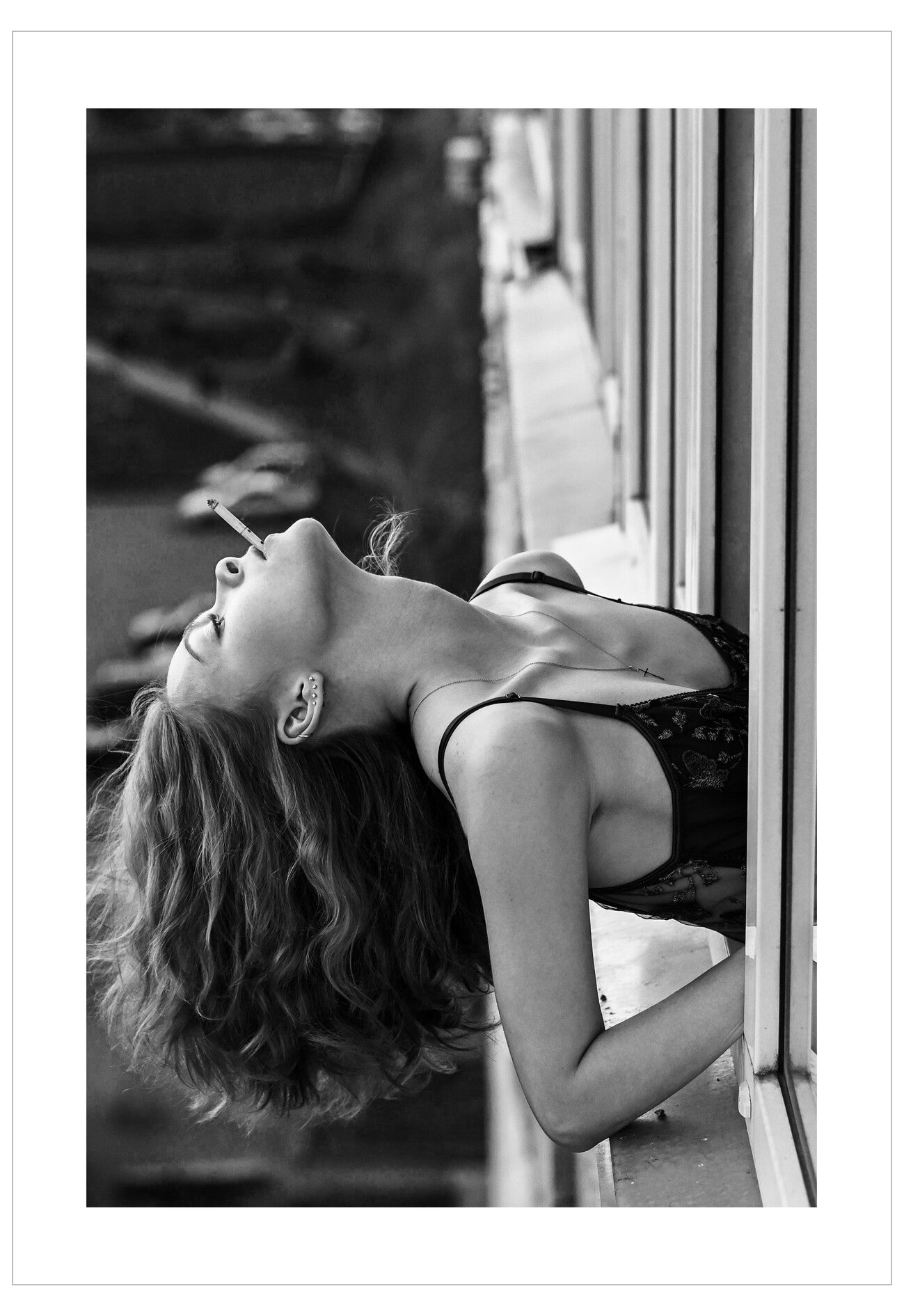 Black and white photo of a woman lying on a couch with a cigarette in her mouth.