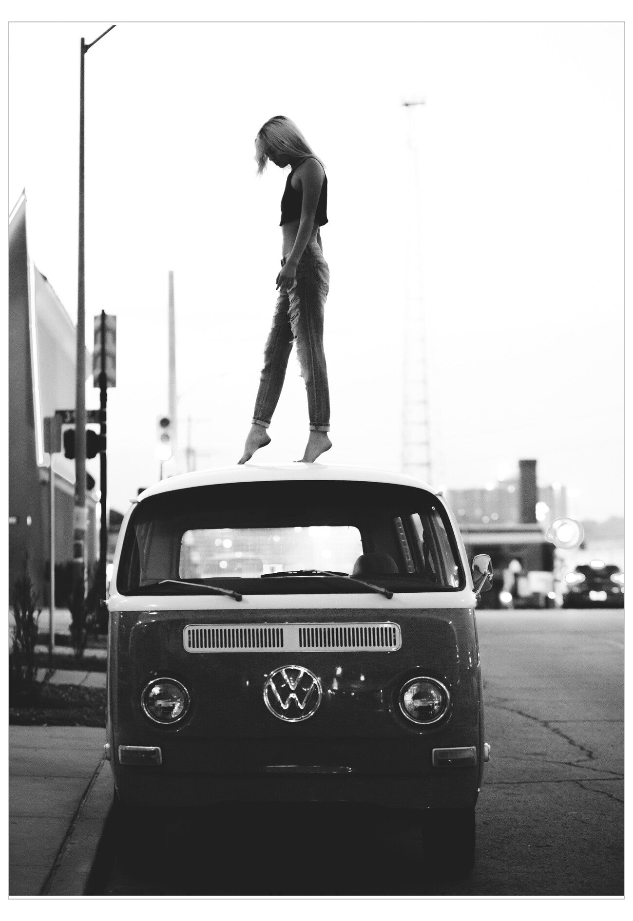 Person standing on the hood of a vintage Volkswagen van in an urban setting