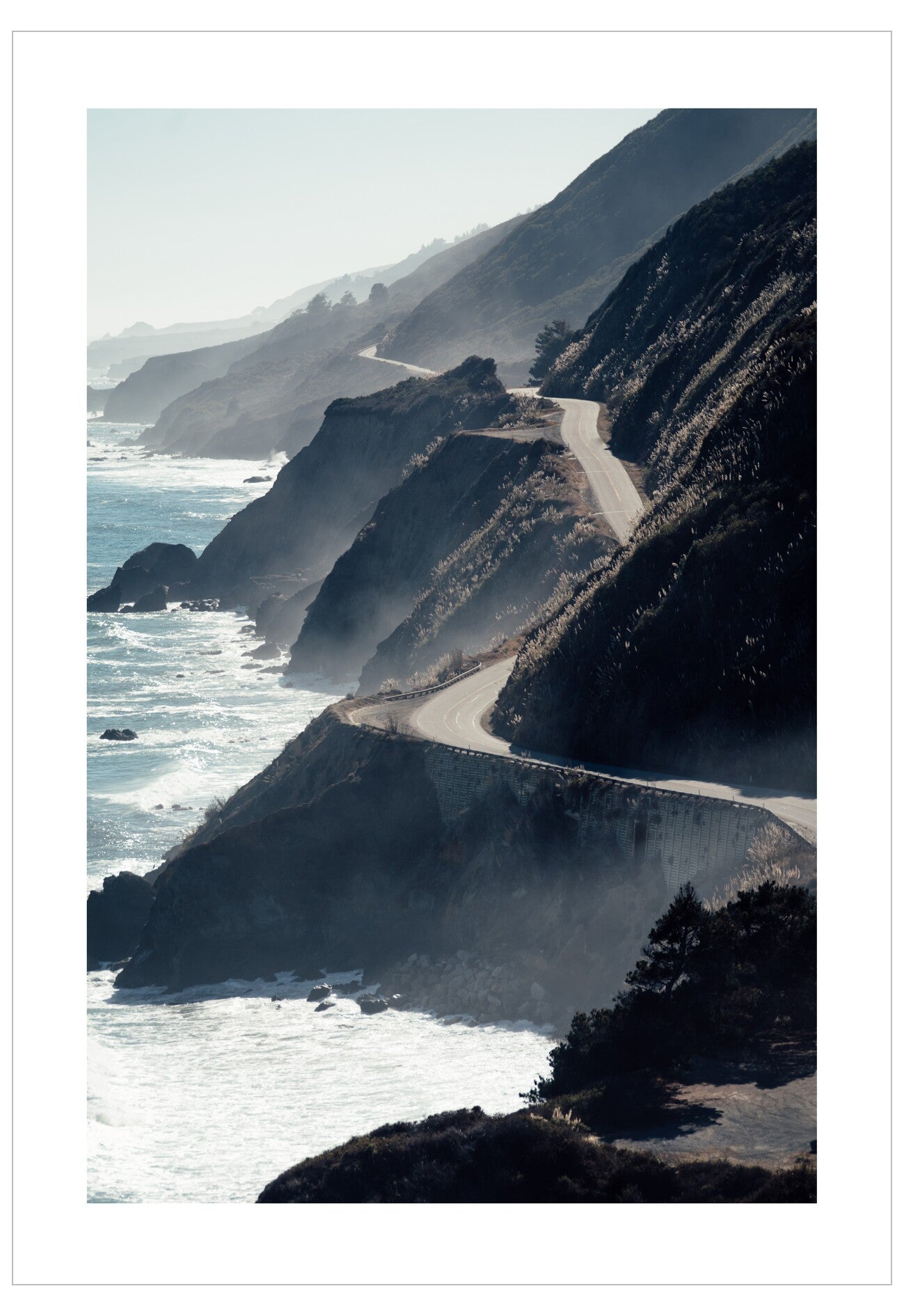 Scenic coastal road along a cliff with ocean waves.