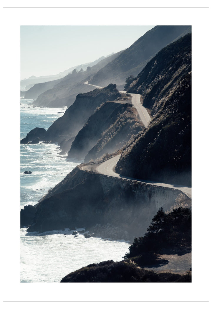 Scenic coastal road along a cliff with ocean waves.