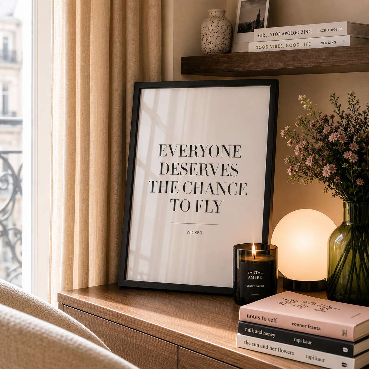 Framed quote on a shelf with books, a candle, and a lamp.