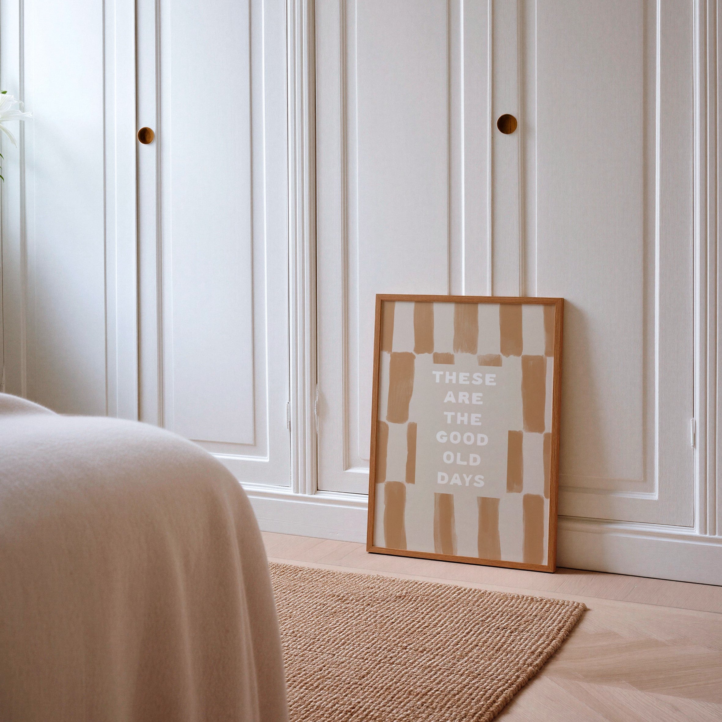 Framed artwork with text on a wooden floor in a bedroom setting
