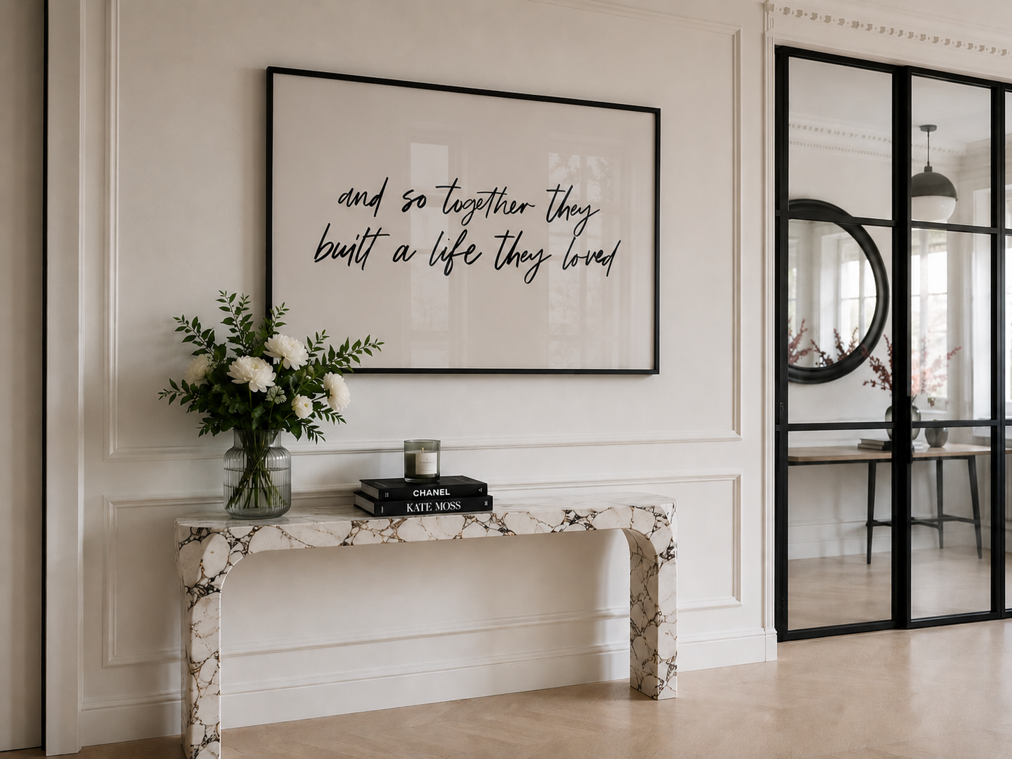 Decorative interior with a console table, flowers, books, and framed quote on a wall.